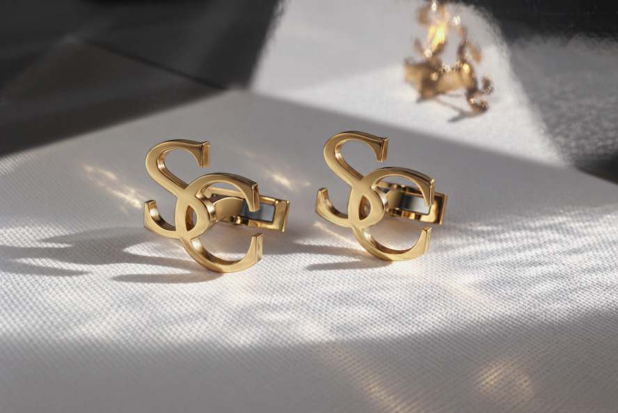 Goldene Manschettenknöpfe mit durchbrochenem Monogramm aus zwei Buchstaben, Vorder- und Rückansicht, Gravur am Verschluss